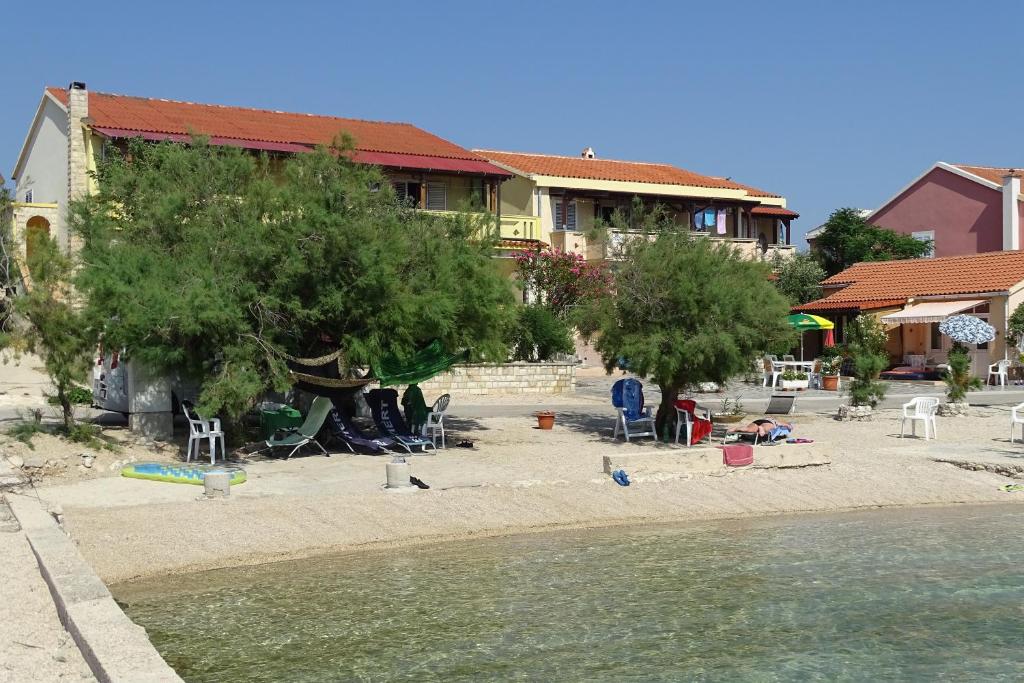 a house on a beach next to a body of water at Apartments Vivien in Kustići