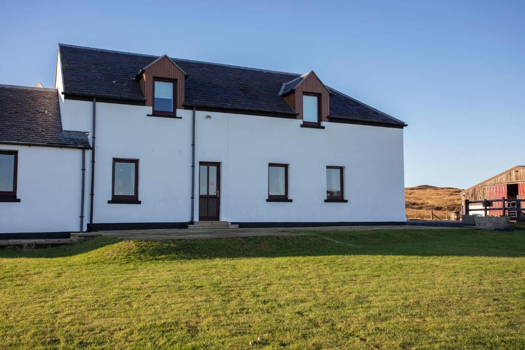 a white house with a black roof at Kentraw Farmhouse Luxury Self Catering in Bruichladdich