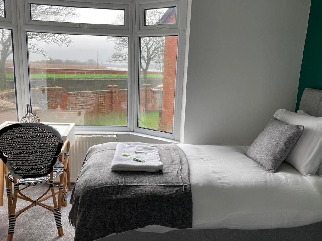 a bedroom with a bed and a chair and a window at Ouse View Cottage in Goole