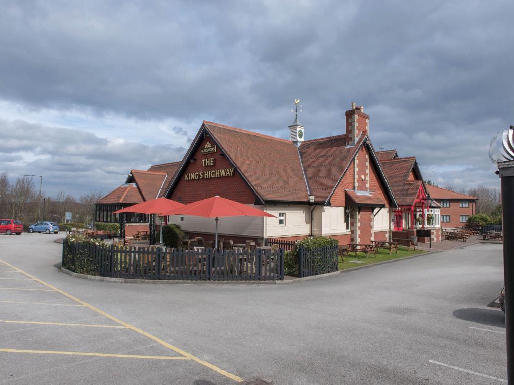 a large building with red umbrellas in a parking lot at Kings Highway, Derby by Marston's Inns in Derby