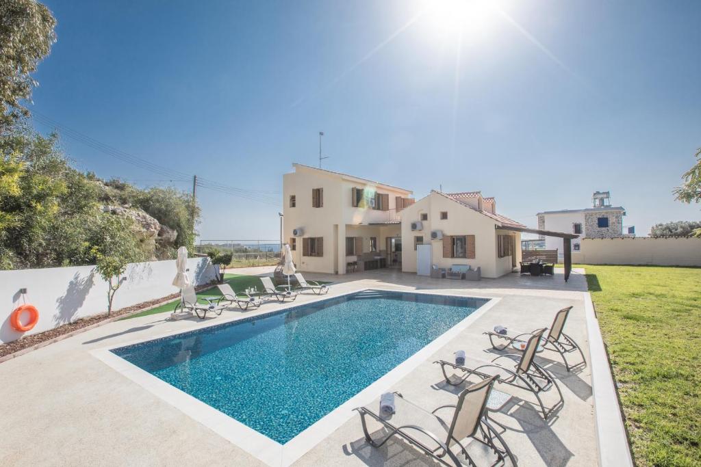 a villa with a swimming pool and chairs at Krasas Villa in Protaras