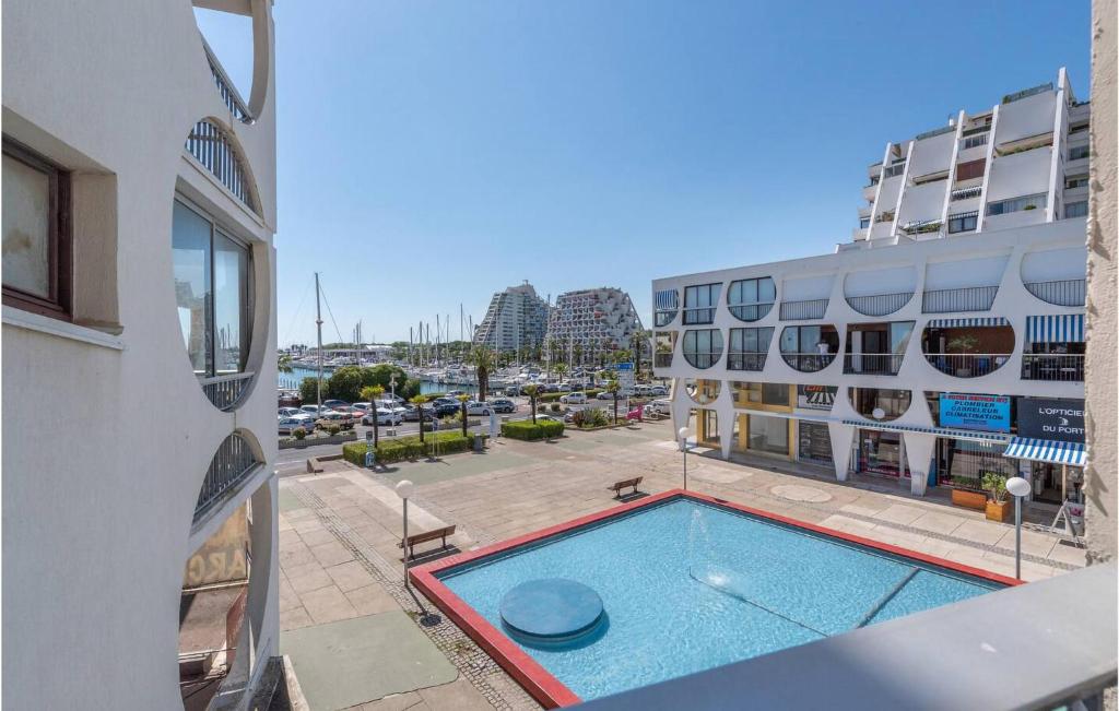 a swimming pool in front of a building with a parking lot at Lovely Apartment In La Grande-Motte in La Grande-Motte