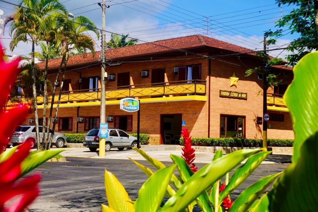 un bâtiment situé dans une rue avec des fleurs devant elle dans l'établissement Pousada Estrela do Mar, à Ubatuba