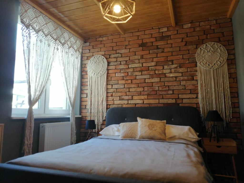 Un dormitorio con una pared de ladrillo y una cama grande en Apartament Jeleń, en Złotów