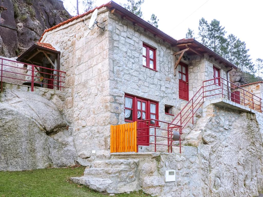Casa de piedra con ventanas rojas y balcón. en Refúgio do Óscar, en Gavieira