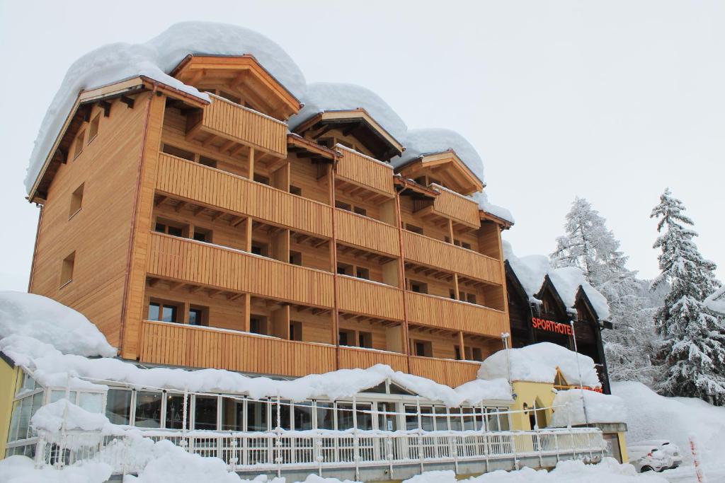 un gran edificio cubierto de nieve frente a él en Sporthotel Oberwald, en Oberwald