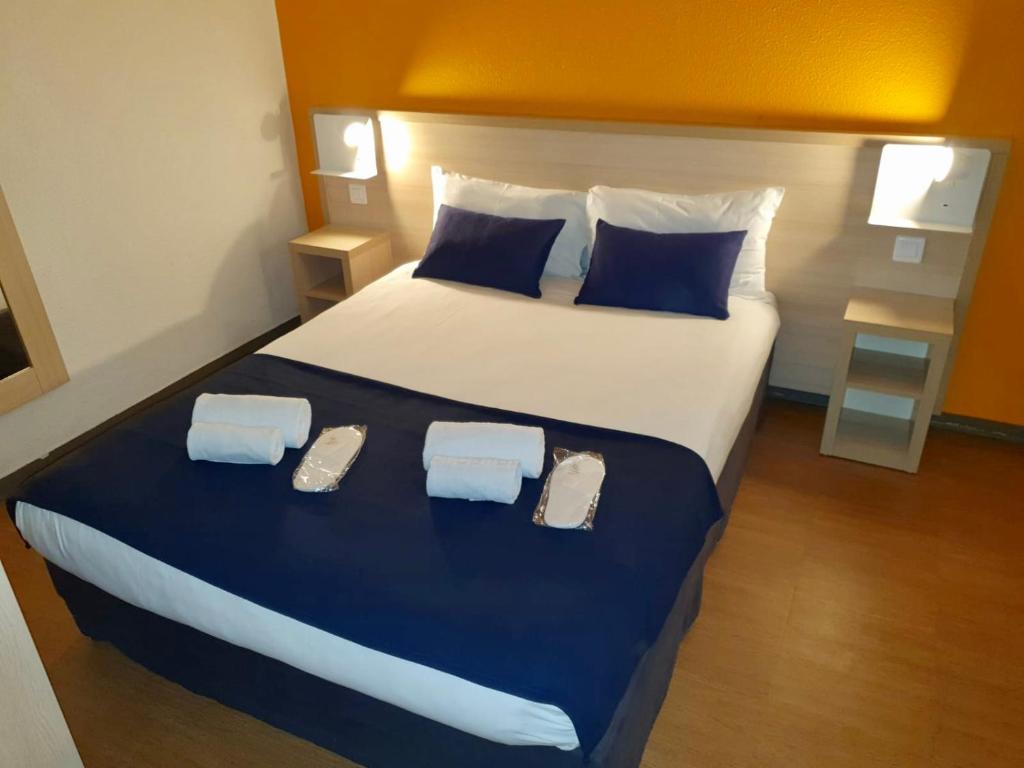 a bedroom with a large bed with two slippers on it at Budget Hotel Melun Sud - Dammarie Les Lys in Dammarie-lès-Lys