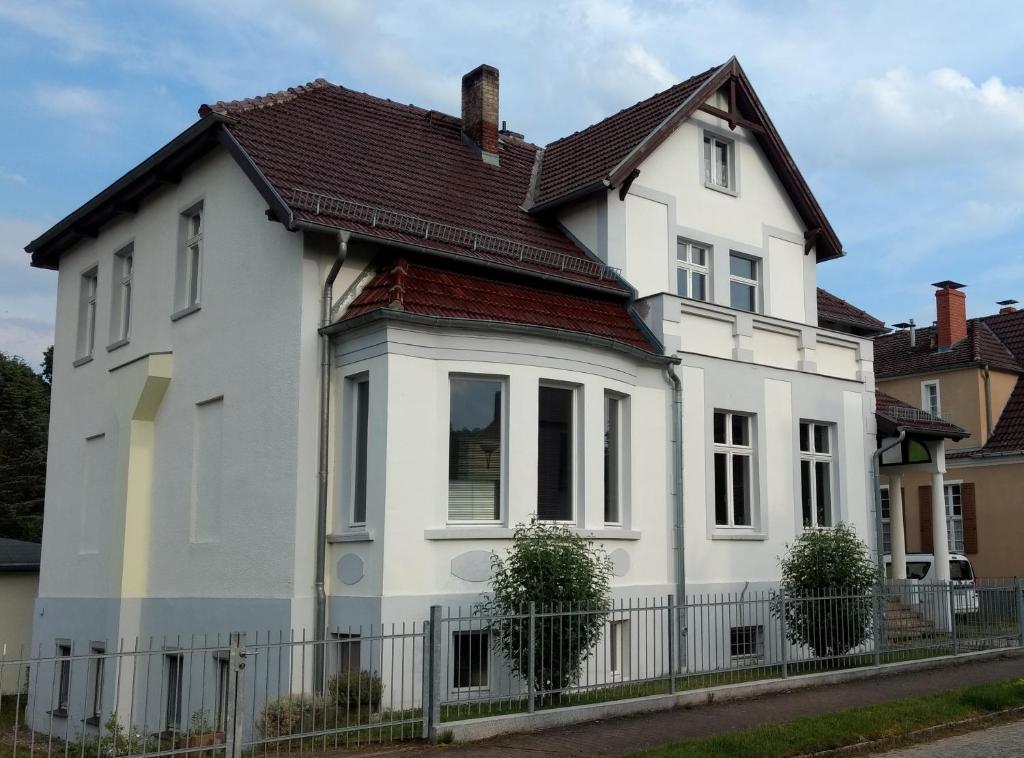 a white house with a brown roof at Pension-Fürstenberghavel Sans Rival in Fürstenberg-Havel
