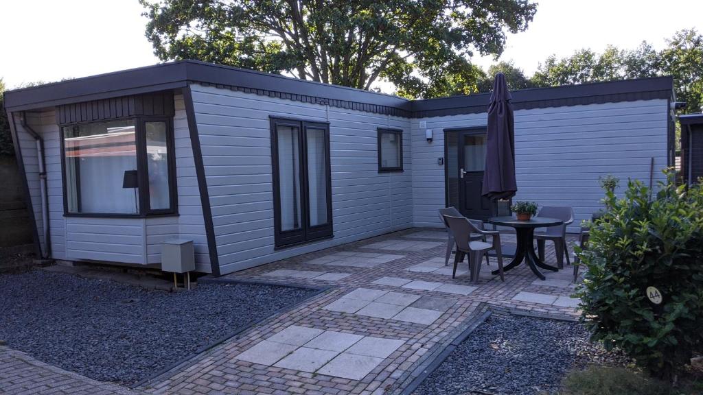 a tiny house with a table and a patio at Chalet Op De Veluwe # Berk in Putten