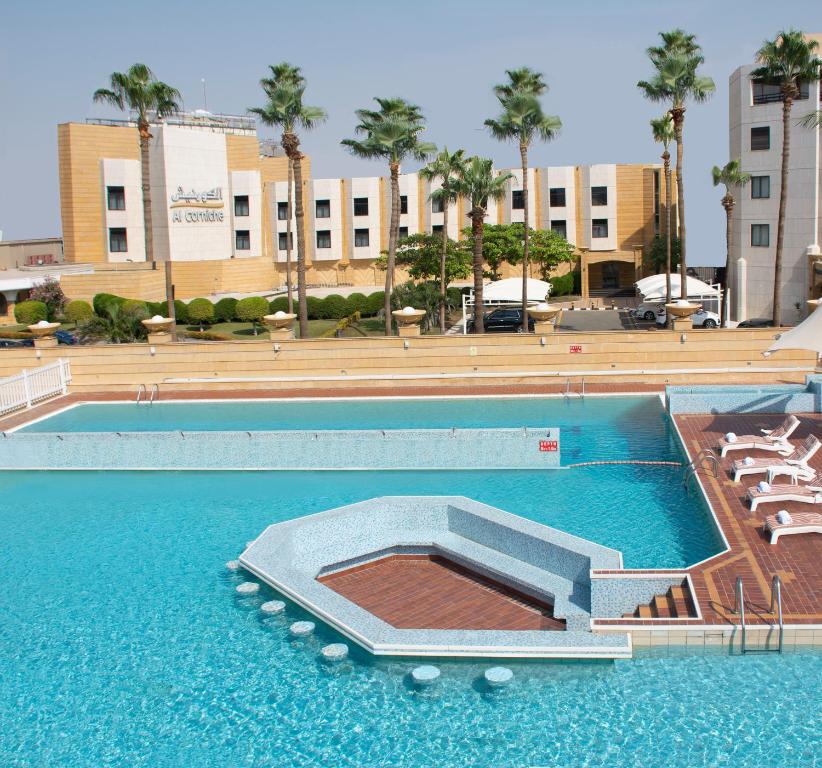 an empty swimming pool with chairs and a building at Al Corniche in Jeddah