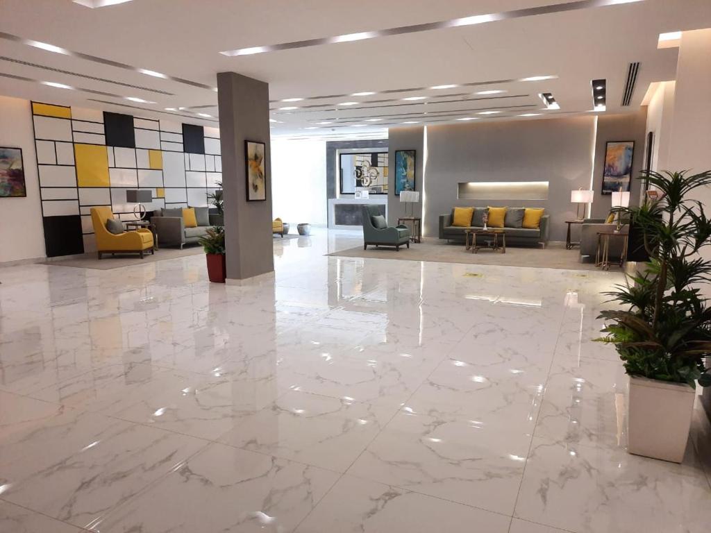 a lobby with a large marble floor and yellow chairs at Executive Suites in Riyadh