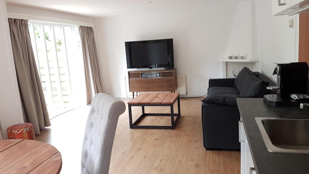 een woonkamer met een bank, een tv en een tafel bij Chalet Op De Veluwe # Linde in Putten