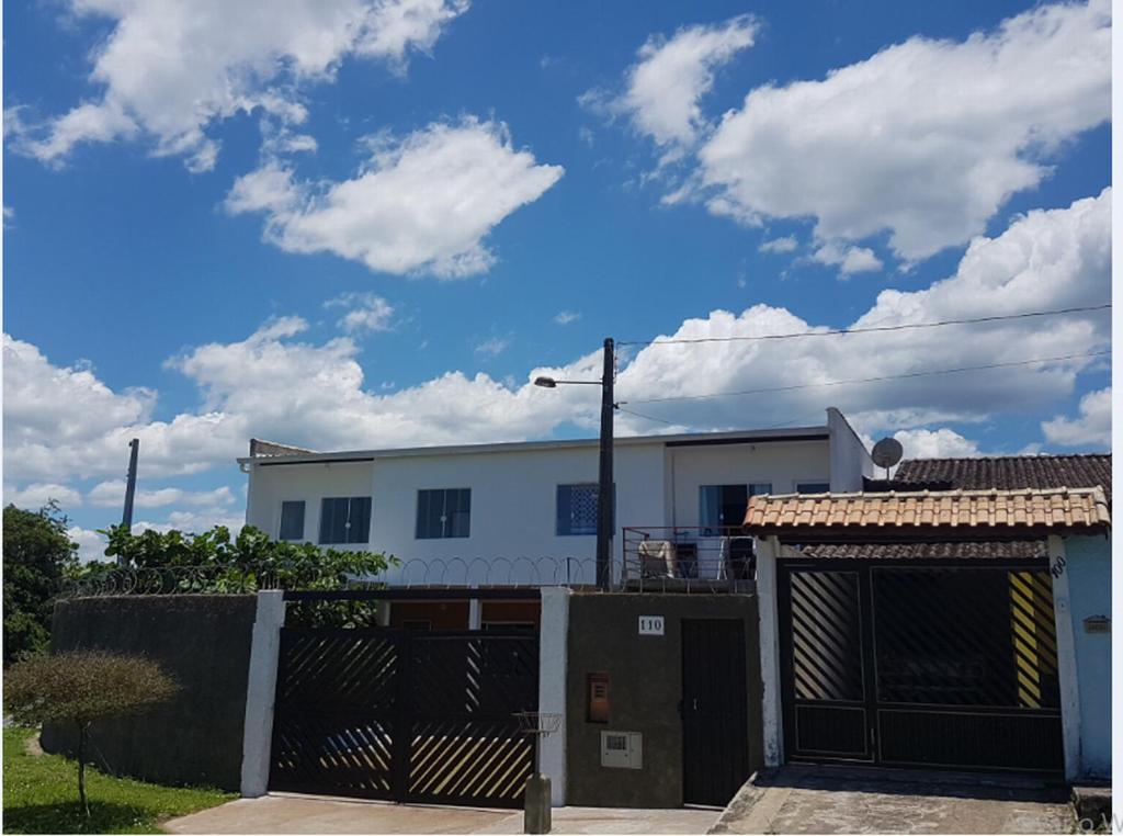 ein weißes Gebäude mit einem Tor und einem Zaun in der Unterkunft Peruíbe - Oasis - Casa espaçosa, lugar tranquilo in Peruíbe