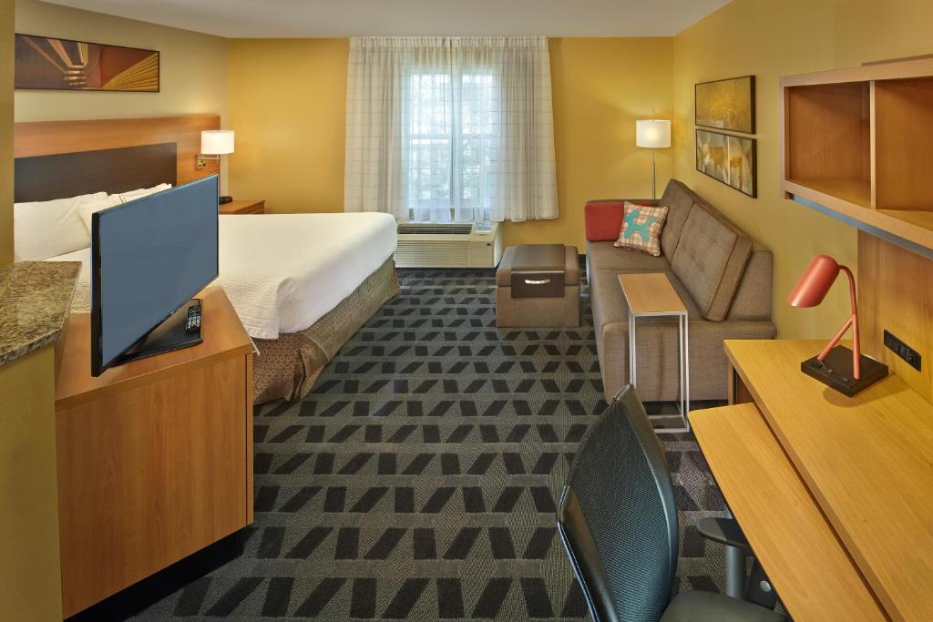 a hotel room with a bed and a television at Residences at Tewksbury in Tewksbury
