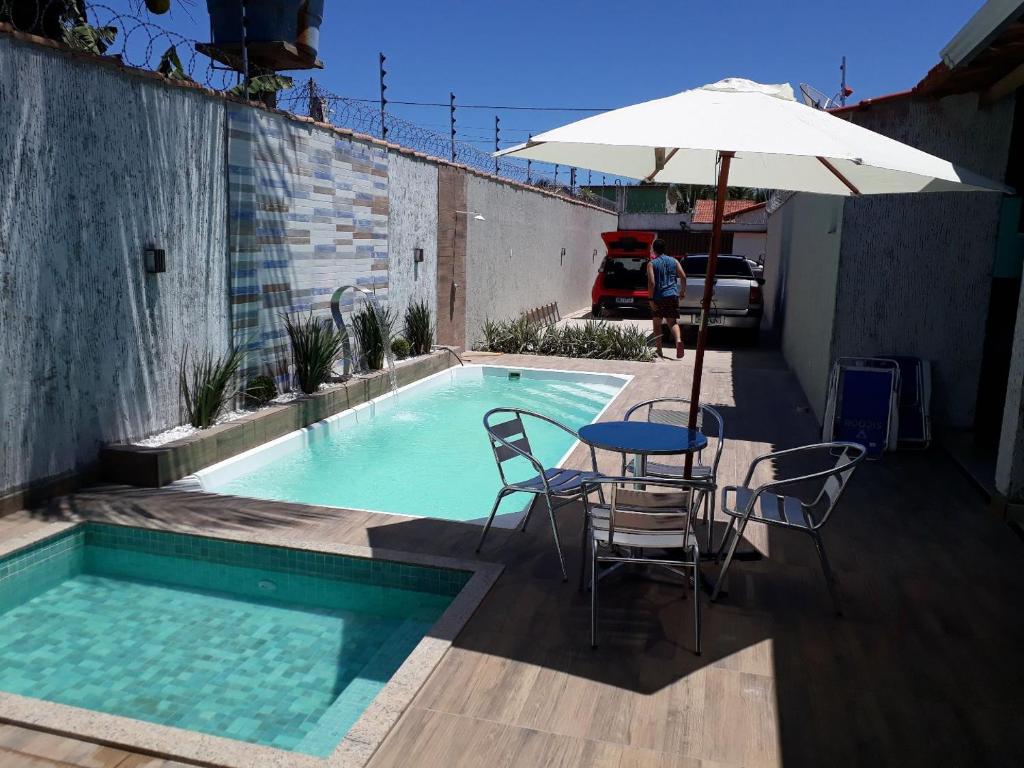 a pool with a table and chairs and an umbrella at Casa Temporada Costa do Atlântico in Alcobaça