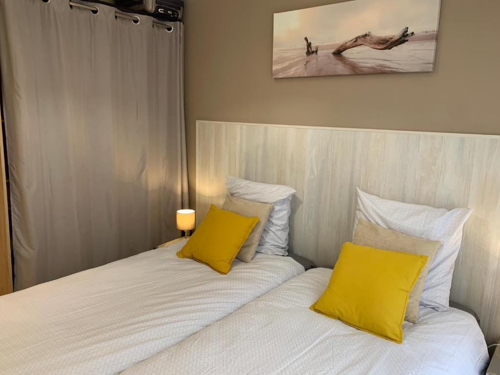 a bedroom with a bed with two yellow pillows at Close Palais - Calm - Brand New in Cannes