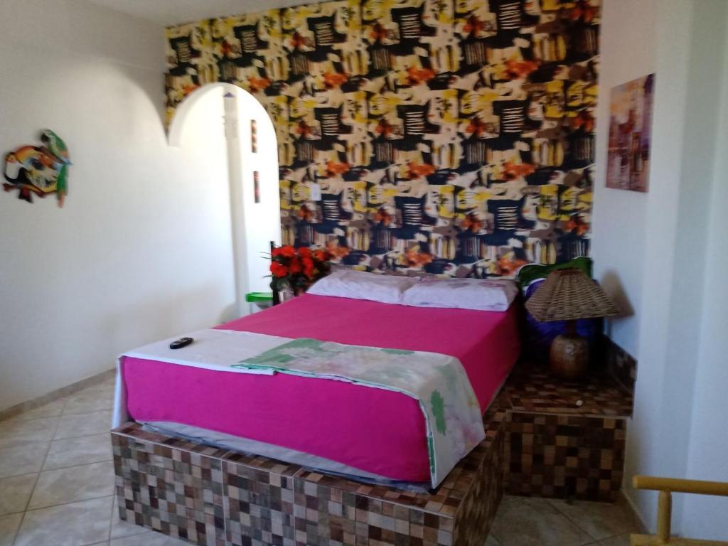 a bed in a room with a wall at Recanto dos Pássaros Olivença in Ilhéus