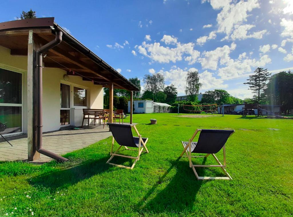 two chairs sitting in the grass next to a house at Domki Ajna Park w uzdrowisku in Kołobrzeg