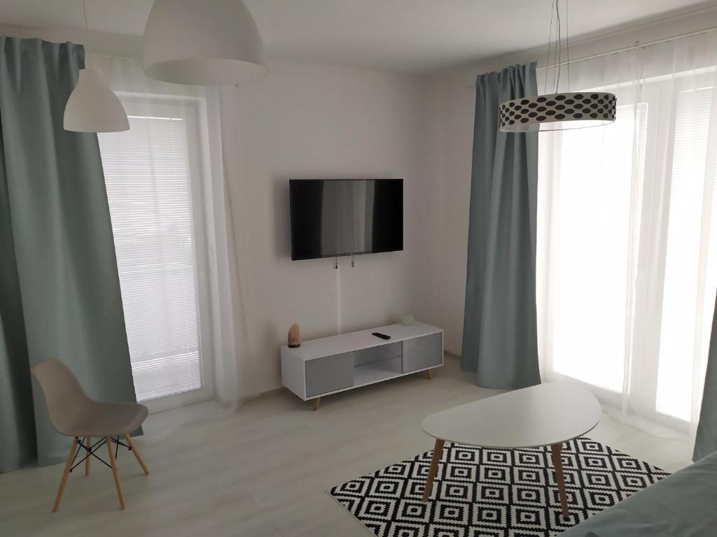 a white living room with a tv and a chair at Apartman TILL in Galanta