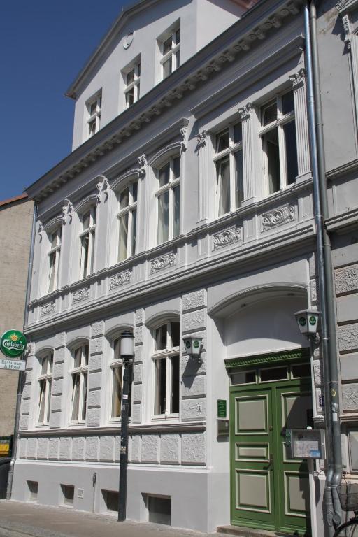 um edifício branco com uma porta verde numa rua em Restaurant & Hotel Olive em Greifswald