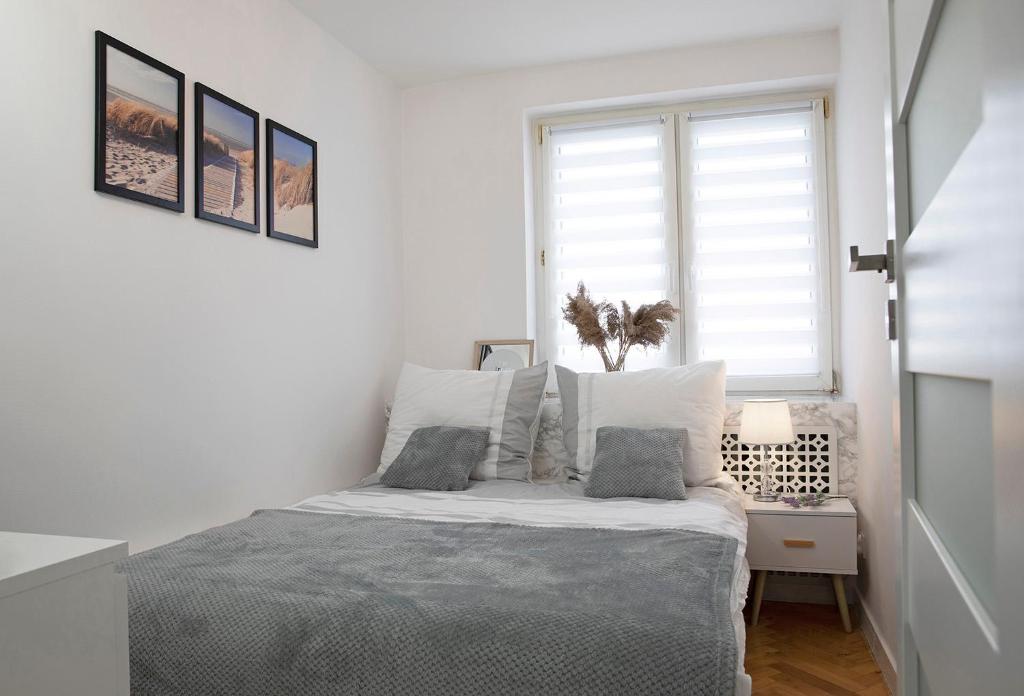 a white bedroom with a bed and a window at Luxus Apartament Sea View Gdynia in Gdynia