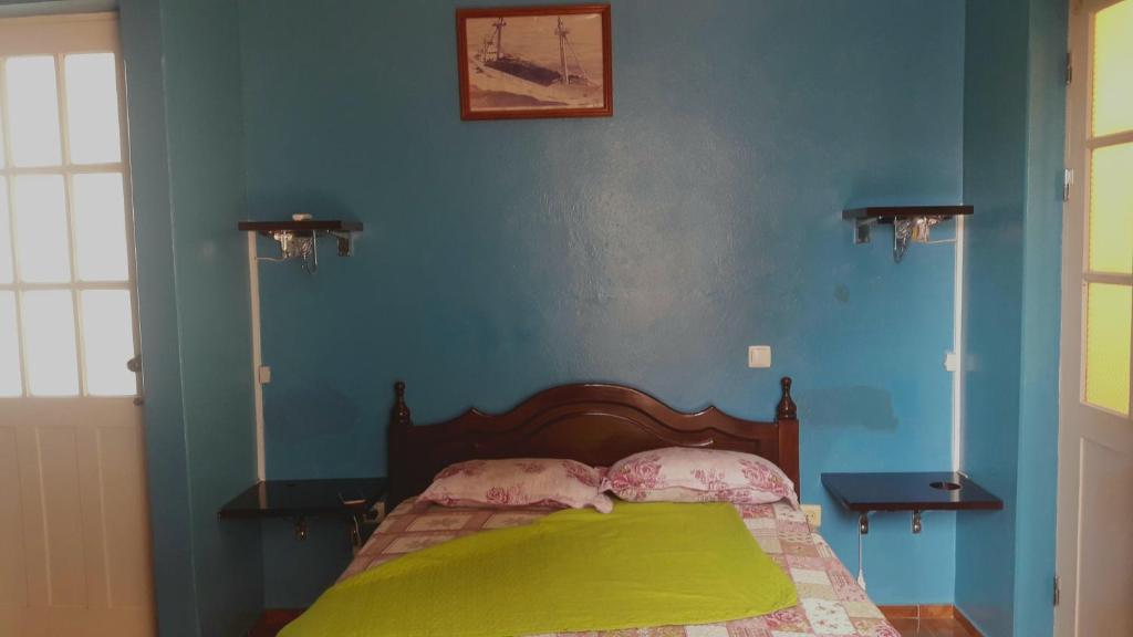 ein Schlafzimmer mit einem Bett mit blauen Wänden und 2 Lampen in der Unterkunft Los Cuartos Man Pretinha in Tarrafal