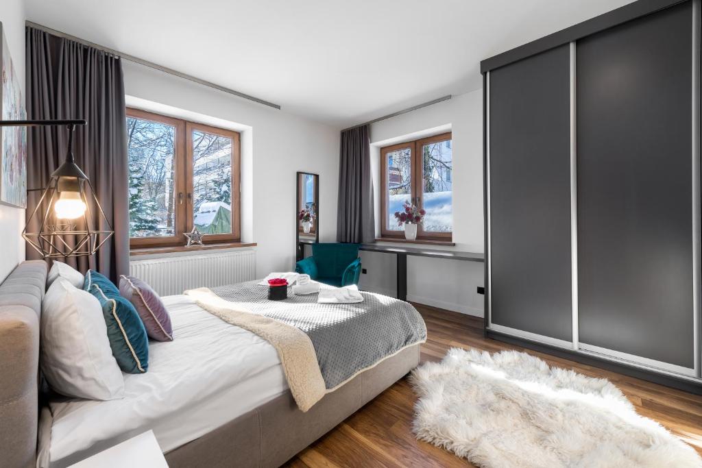 een slaapkamer met een bed, een bank en ramen bij Willa Jarosta in Zakopane