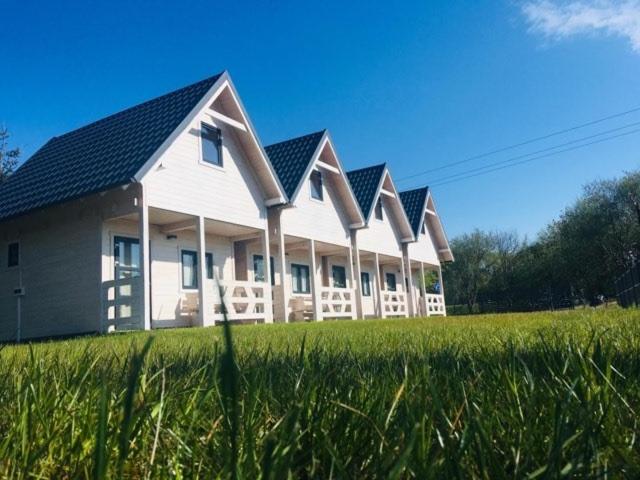 une rangée de maisons dans un champ d'herbe dans l'établissement Domki Letniskowe Kaja, à Rewal