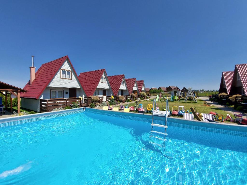 a large swimming pool in front of a house at Domki Letniskowe Słońce in Gąski