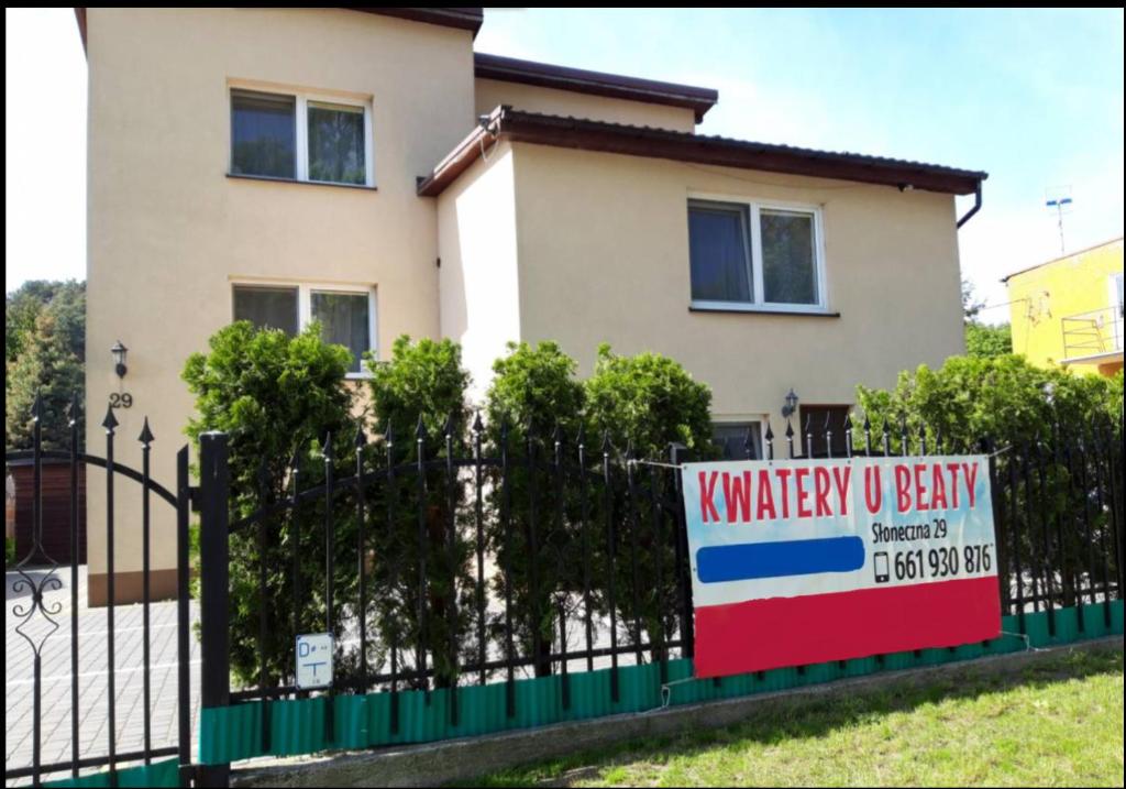 Kwatery u Beaty في Krynica Morska - Piaski: علامة على سياج أمام المنزل