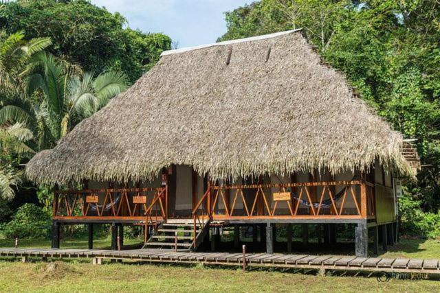 uma grande cabana com um telhado de palha e uma escada em Nicky Amazon Lodge em Marian