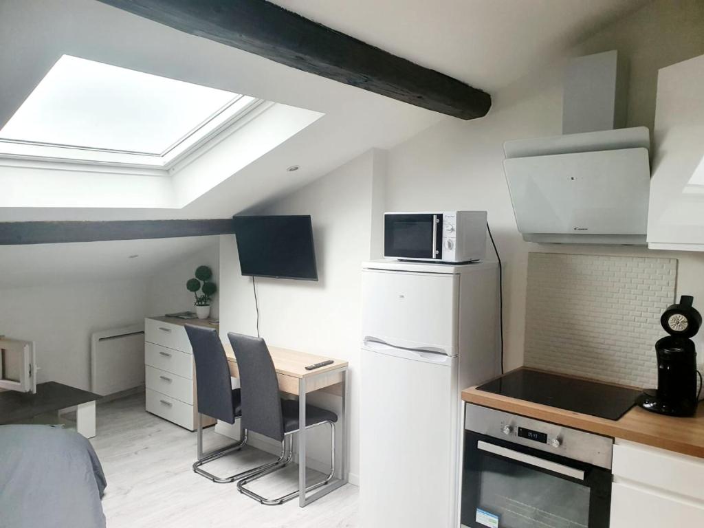 een keuken met een koelkast en een bureau met stoelen bij Beau Studio Centre Ville Paul Bert in Valence