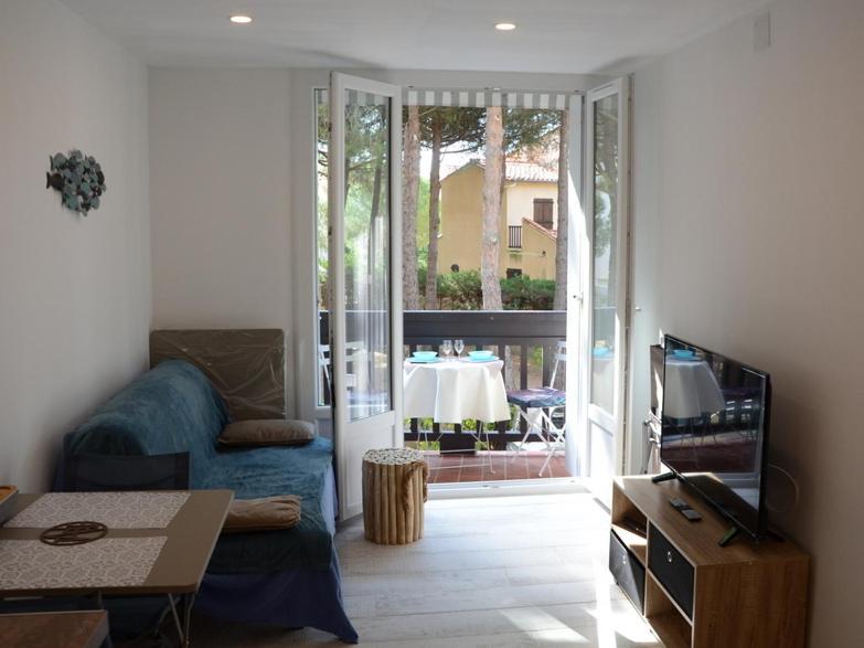 un salon avec un canapé, une télévision et une table dans l'établissement T2 au calme avec clim 100 m plage, classé 2 étoiles, à Argelès-sur-Mer