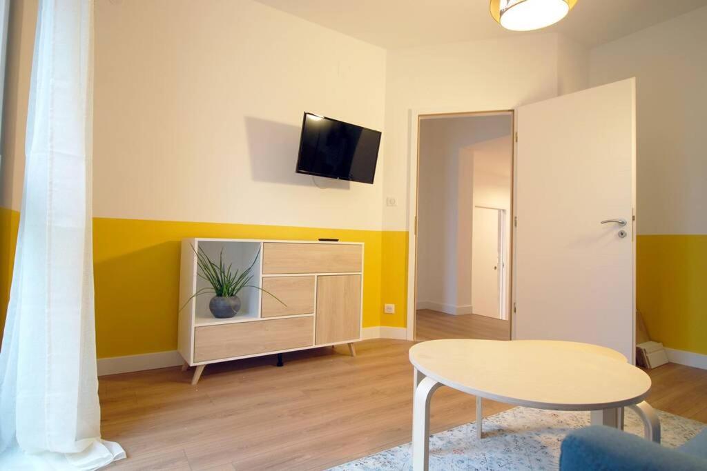 ein Wohnzimmer mit einem Tisch und einem TV an der Wand in der Unterkunft B&B jaune, Appartement indépendant, parking, wifi près de Strasbourg in Ittenheim