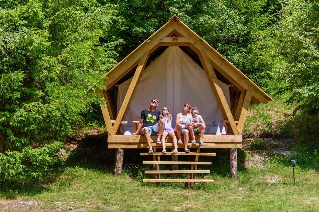un grupo de tres personas sentadas frente a una tienda en Adrenaline Check Camping, en Bovec