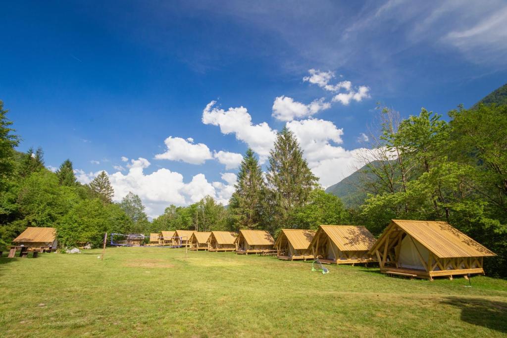
a row of wooden picnic tables in a grassy field at Adrenaline Check Camping in Bovec
