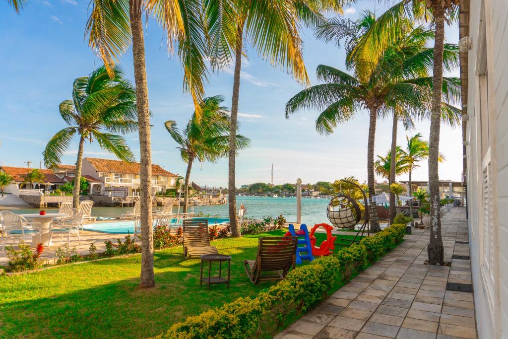 um resort com palmeiras e uma piscina em Pousada Marilia em Cabo Frio
