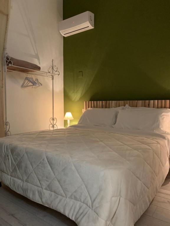 a bedroom with a white bed with a green wall at AGRIB&B Il Pomo d'oro in Assemini