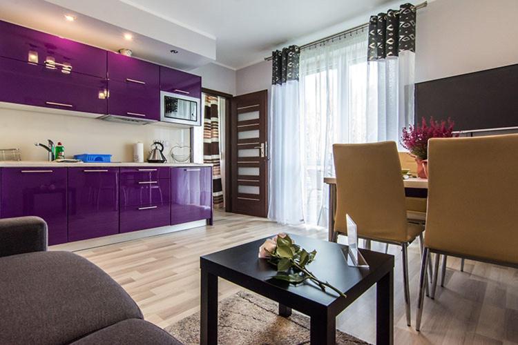 a living room with purple cabinets and a table at Apartament Wrzosowy - 5D Apartamenty in Świeradów-Zdrój