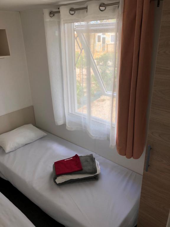 uma cama num quarto com uma janela em CANET Plage Mobil Home Nicky em Canet-en-Roussillon
