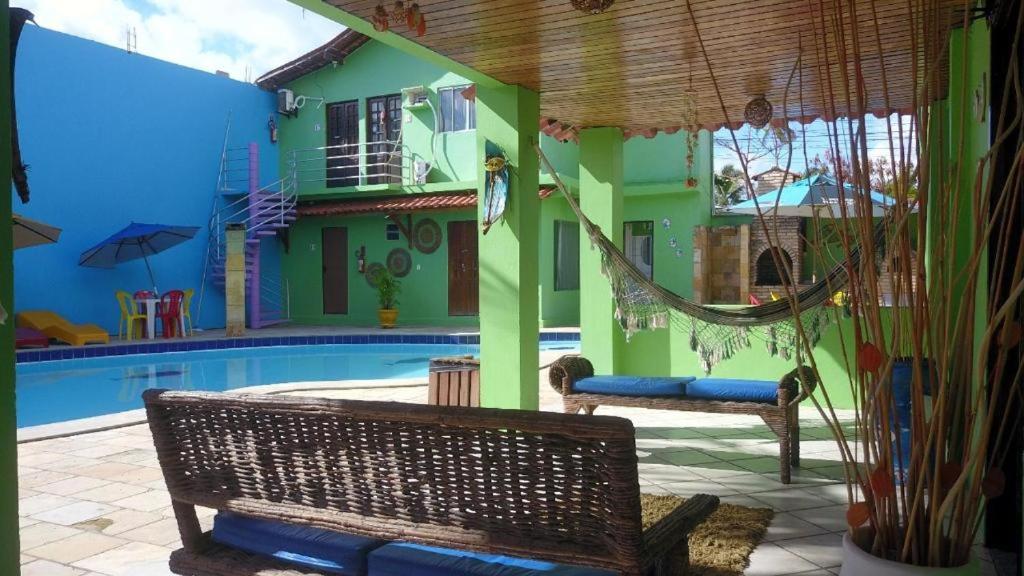 une maison avec un hamac à côté d'une piscine dans l'établissement Pousada Verde Suites, à Porto de Galinhas
