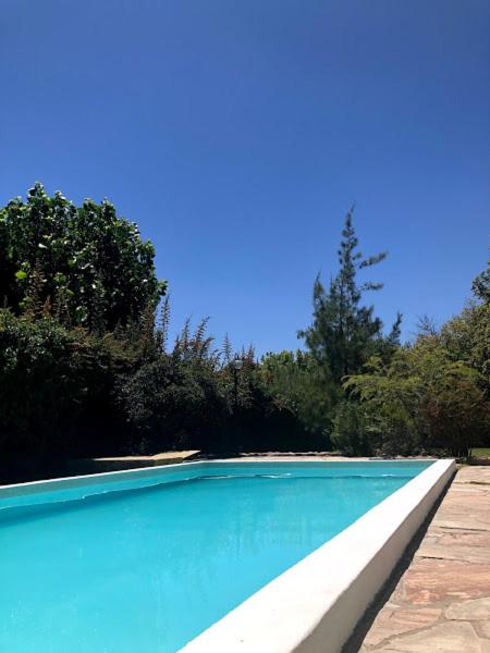 a blue swimming pool with trees in the background at Casa Drummond in Ciudad Lujan de Cuyo