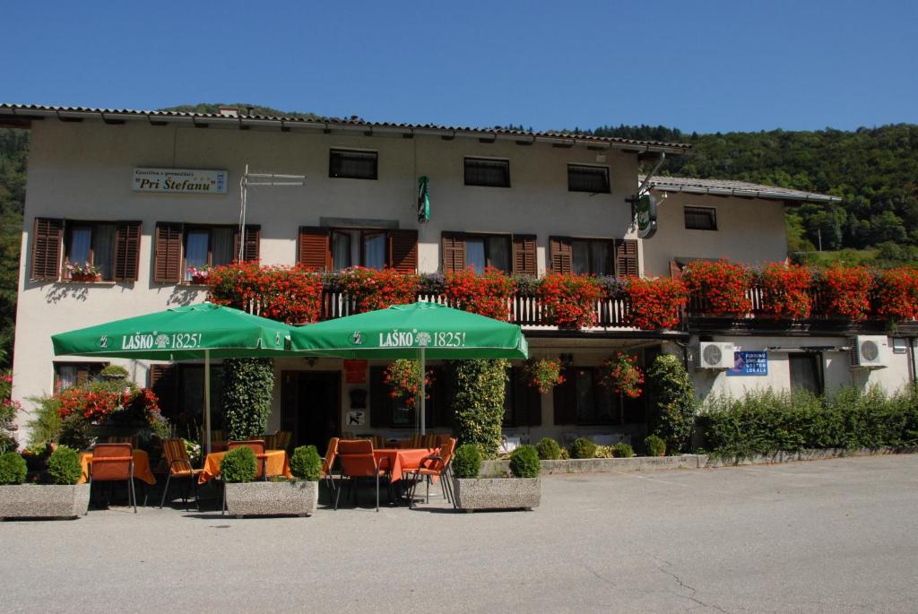 un edificio con sillas y sombrillas delante de él en Guesthouse Pri Štefanu, en Most na Soči