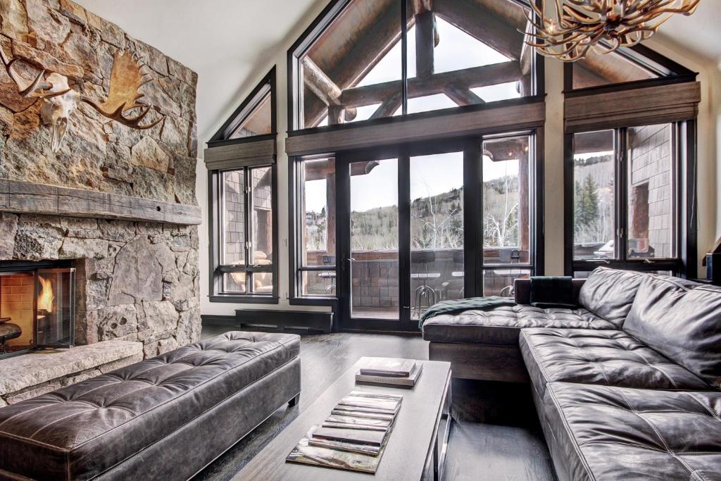 a living room with a couch and a stone fireplace at Stunning 4 bedroom condo Snowcloud base of Bachelor Gulch condo in Avon