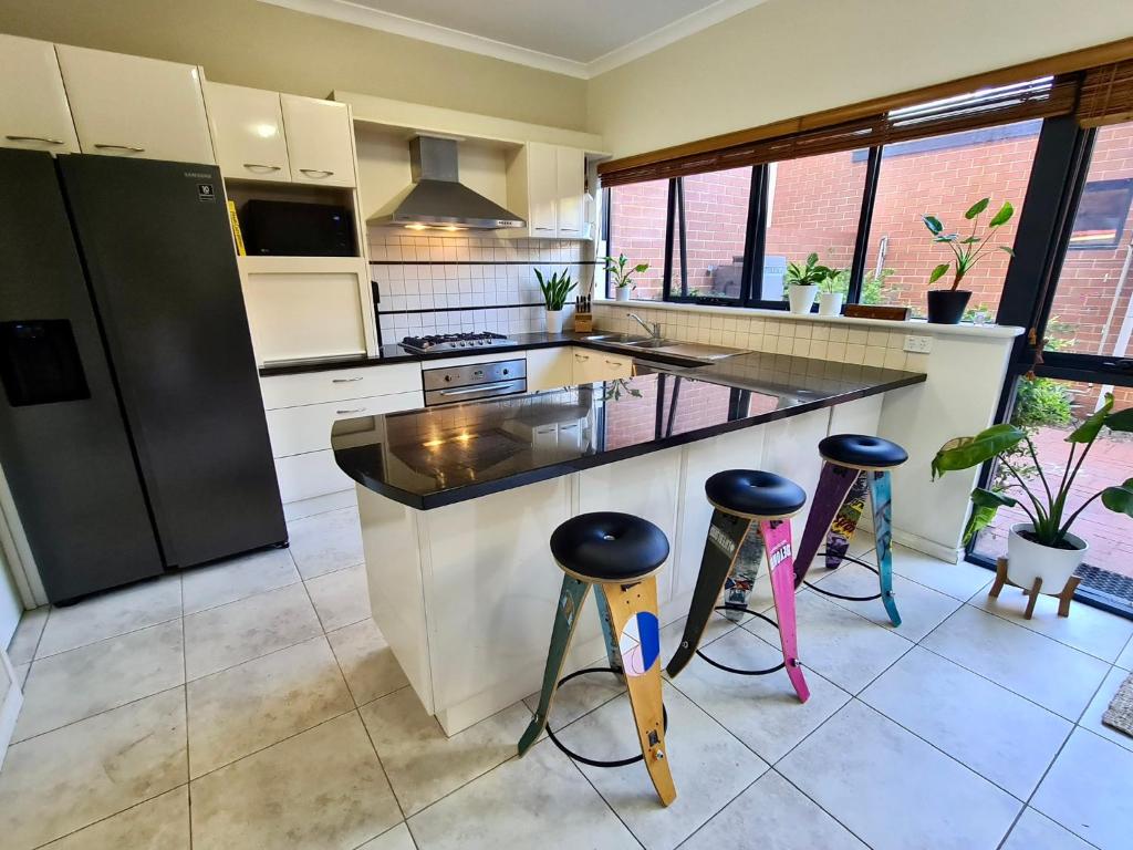 a kitchen with a counter and stools in it at Sunset views over South Fremantle in Fremantle