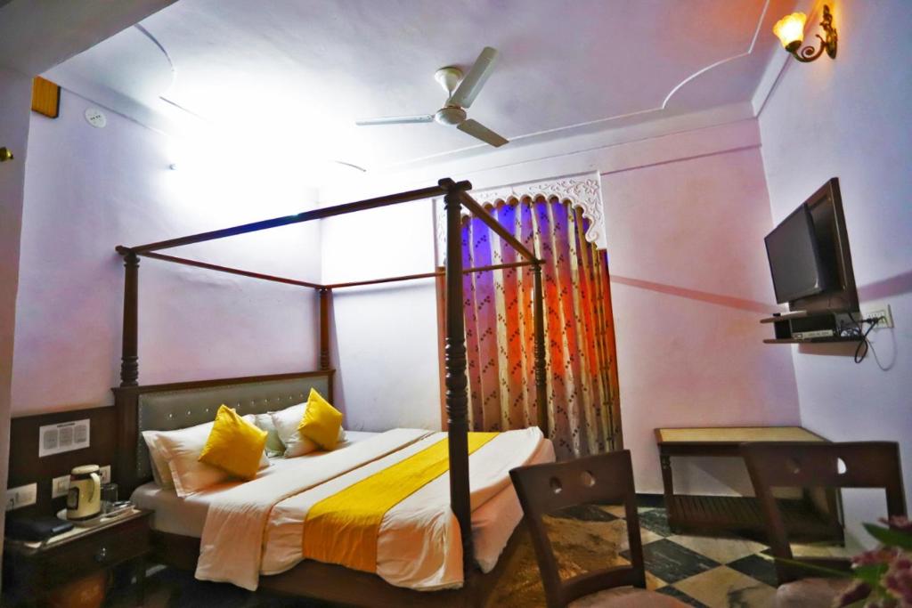 een slaapkamer met een hemelbed en een televisie bij Hotel Rang Sagar Haveli in Udaipur