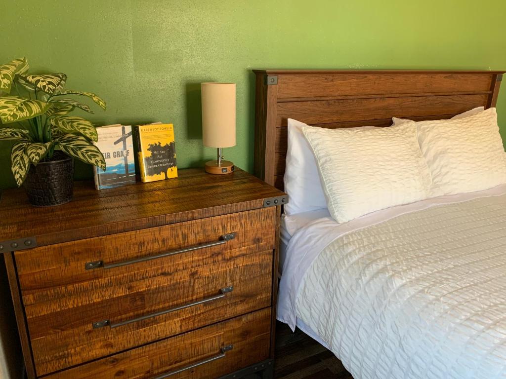 ein Schlafzimmer mit einem Bett und einer Holzkommode mit einer Lampe in der Unterkunft Trailhead Suites in Marysville