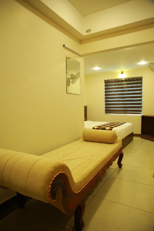 two beds in a room with a window at KALATHIL TOURIST HOME in Kunnamkulam