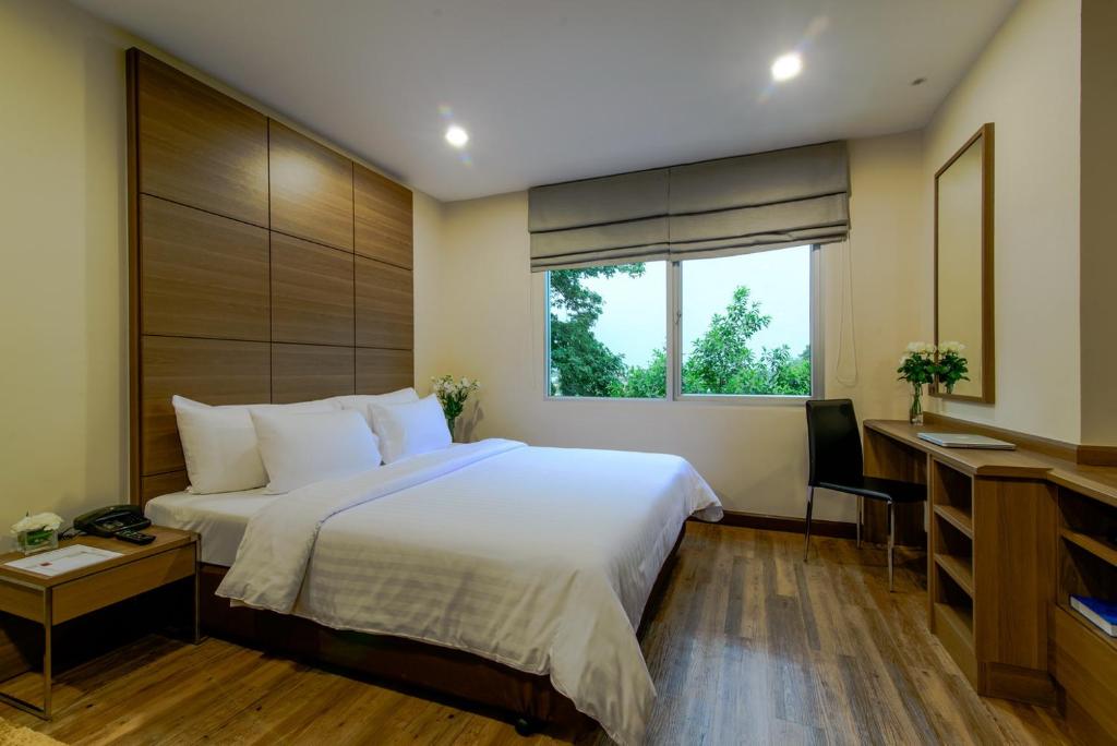 a bedroom with a bed and a desk and a window at Sima Thani Hotel in Nakhon Ratchasima