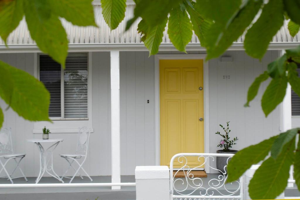 a yellow door on a white house with a table and chairs at Mary Lemon Cottage - Heritage Home in Orange